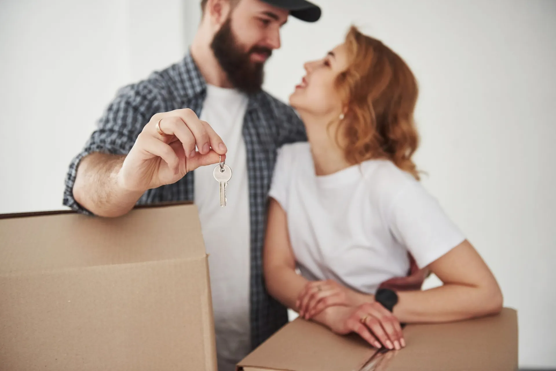 Pareja feliz recibiendo las llaves de su nueva vivienda entre cajas de mudanza
